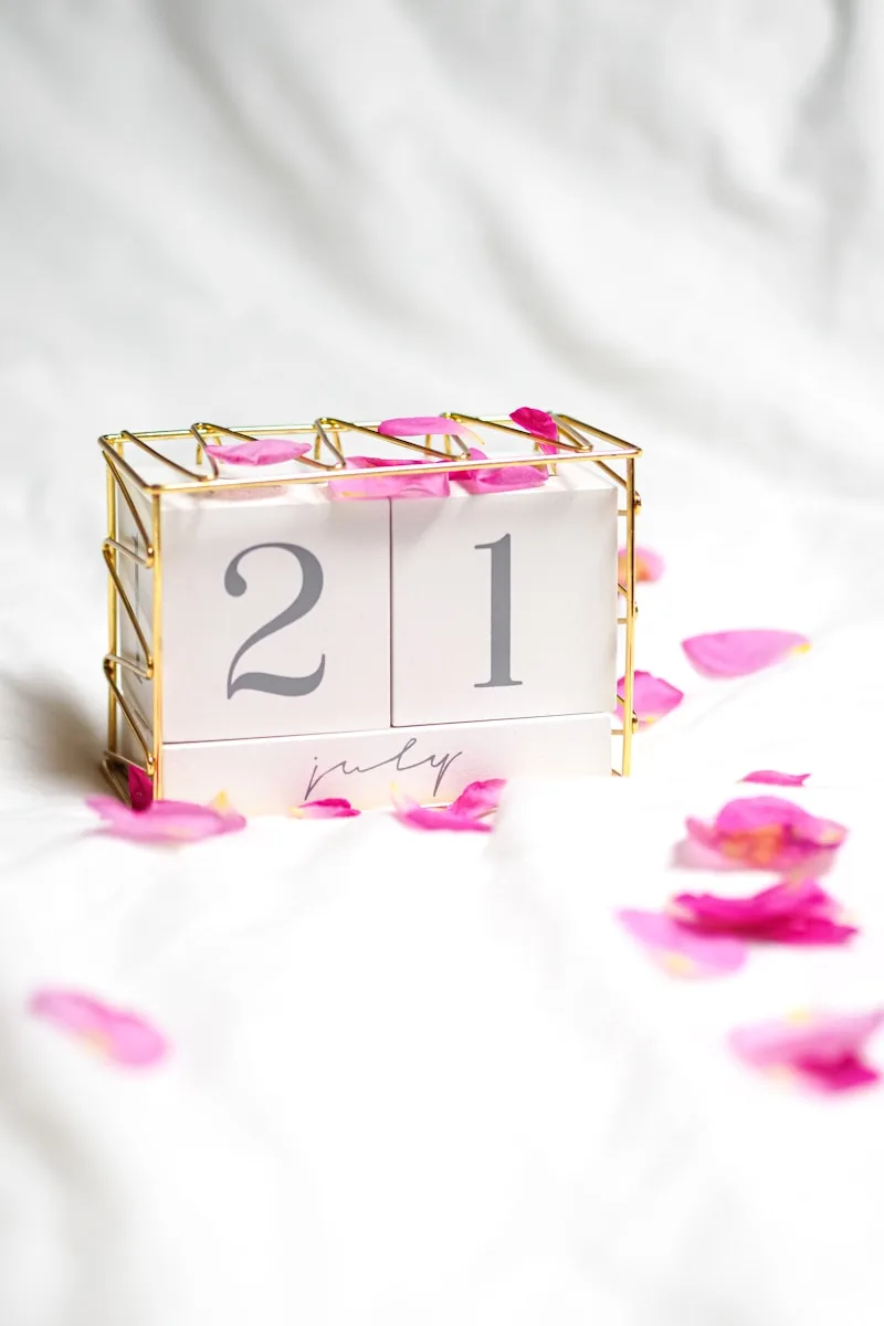 a small calendar with pink petals on a white surface